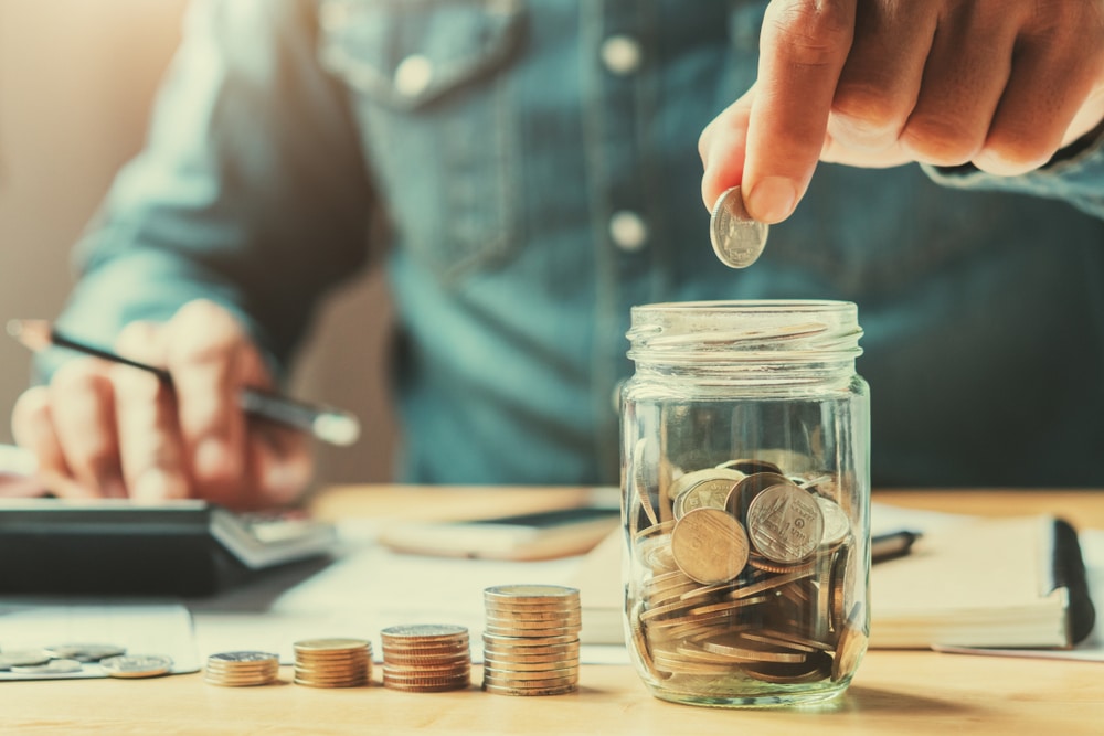 How to save 10k in a year saving money and earning more money a man counting pennies into a jar